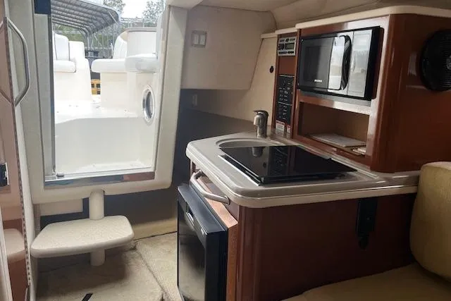 Slide: The Image of Interior of 2008 Sea Ray 240 Sundancer boat with kitchenette and seating area. - 14