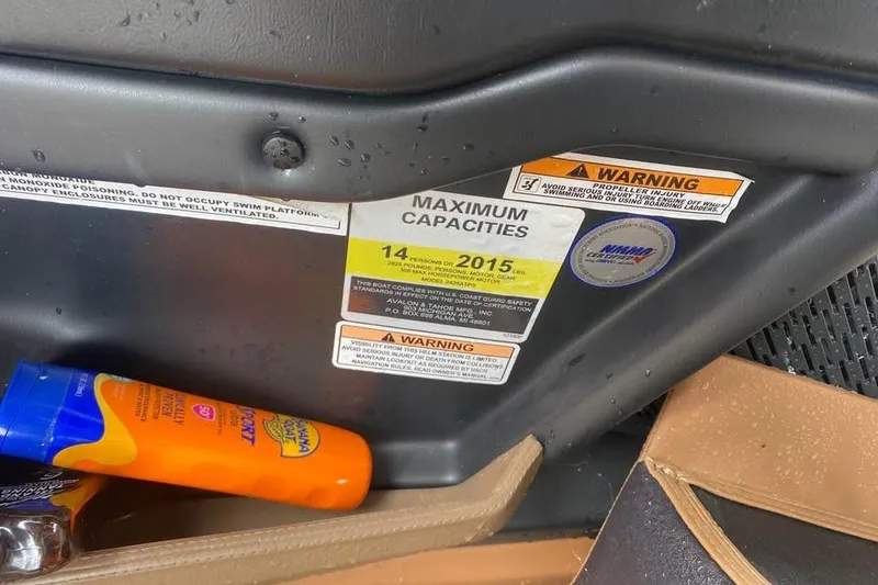 Slide: The Image of 2024 Avalon Catalina 2585 RL boat capacity and safety warnings with sunscreen bottle nearby. - 16