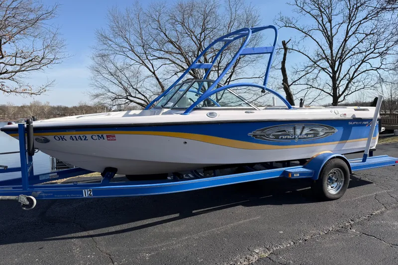 Slide: The Image of 2004 Nautique Super Air Nautique 210 boat on trailer, parked near a lake. - 8