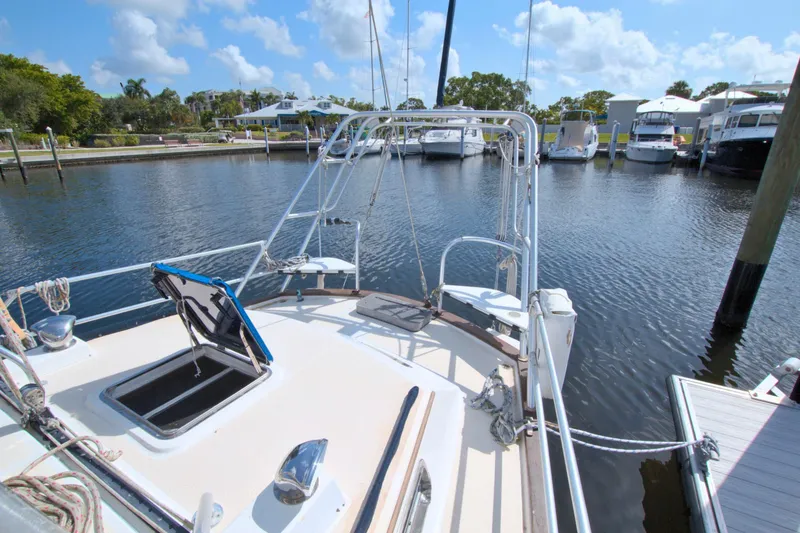Slide: The Image of 1987 Morgan 43 CC sailboat docked in a serene marina under a clear blue sky. - 12