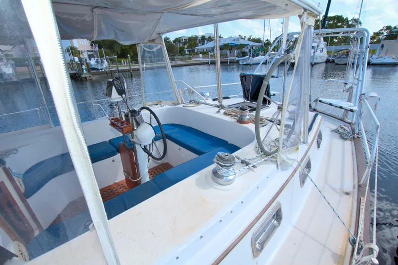 Slide: The Image of 1987 Morgan 43 CC sailboat cockpit with blue seating, steering wheel, and marina view. - 23