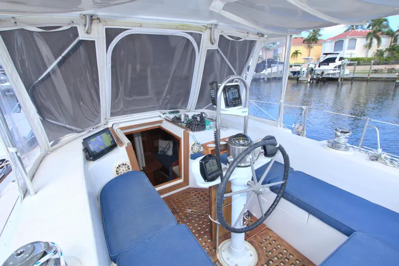 Slide: The Image of 1987 Morgan 43 CC yacht cockpit with navigation equipment and blue seating by the water. - 25
