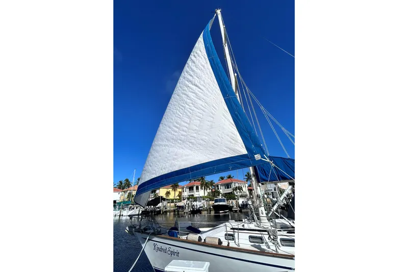 Slide: The Image of 1987 Morgan 43 CC sailboat with blue and white sails docked in a marina. - 4