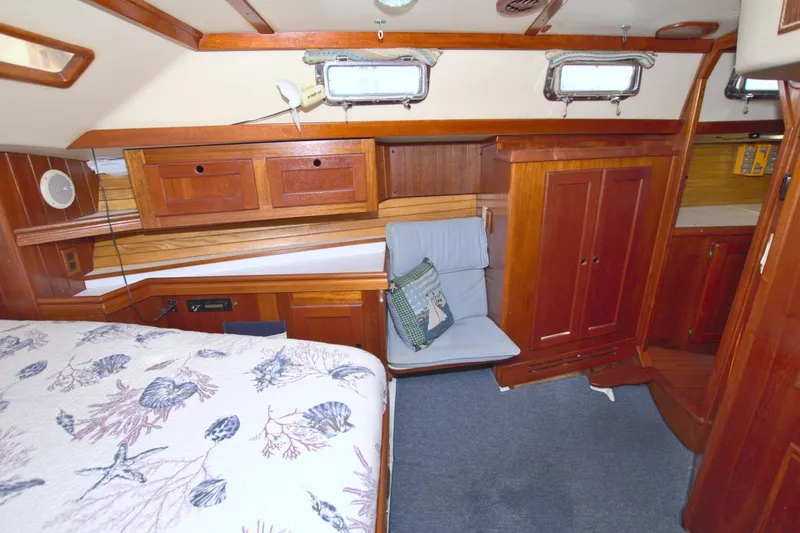 Slide: The Image of 1987 Morgan 43 CC yacht interior with wooden cabinetry and nautical-themed bedding. - 53