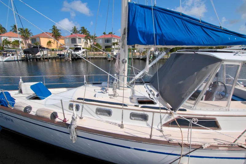 Slide: The Image of 1987 Morgan 43 CC sailboat docked in a sunny marina, featuring blue sail covers. - 8