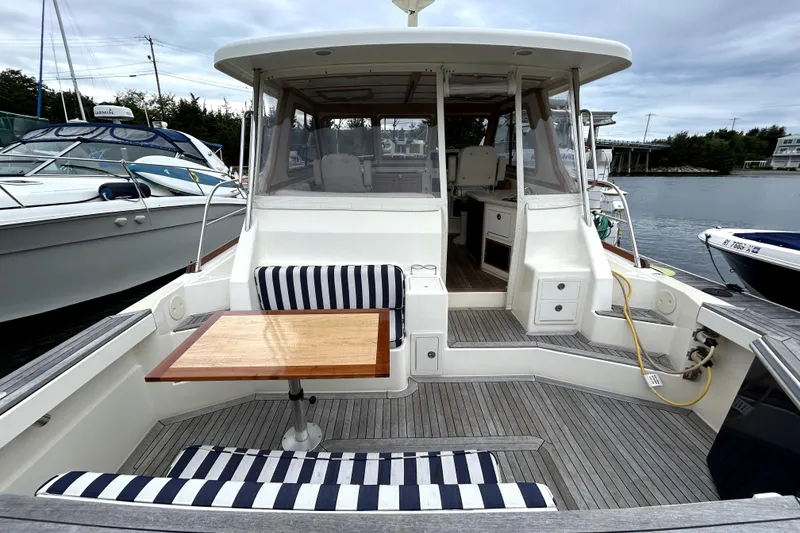 Slide: The Image of 2006 Sabre 38 Hard Top Express boat with striped seating and wooden table on deck. - 3