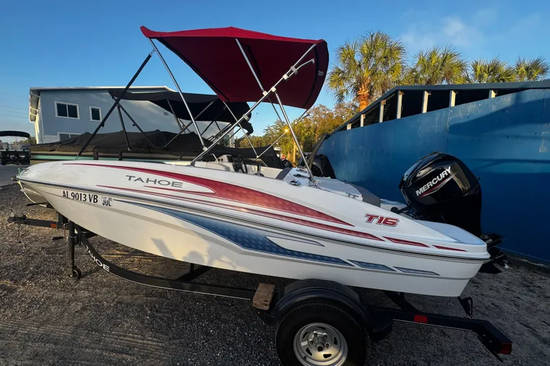 The Image of 2024 Tahoe T16 boat with red canopy and Mercury engine, parked outdoors. - 0