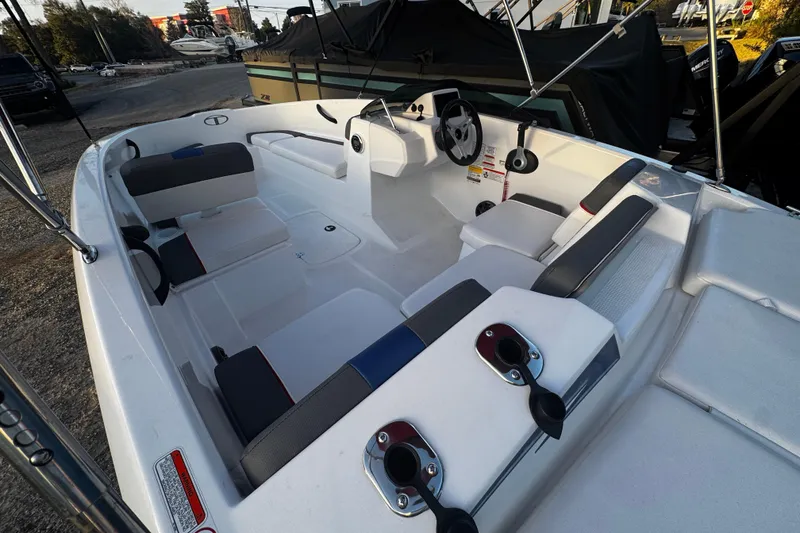Slide: The Image of 2024 Tahoe T16 boat interior with seating and steering wheel, docked outdoors. - 2