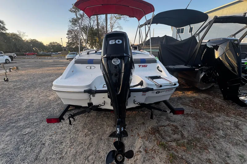 Slide: The Image of 2024 Tahoe T16 boat with 60 HP outboard motor, parked outdoors. - 6