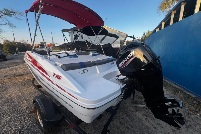 Slide: The Image of 2024 Tahoe T16 boat with Mercury engine, parked on a trailer, featuring a red canopy. - 7