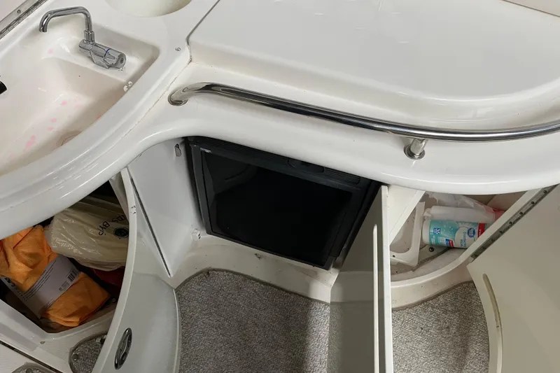 Slide: The Image of 2003 Sea Ray 290 Bowrider interior with sink, storage compartments, and toiletries. - 11
