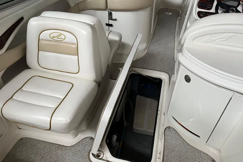 Slide: The Image of 2003 Sea Ray 290 Bowrider interior with white seating and open storage compartment. - 13