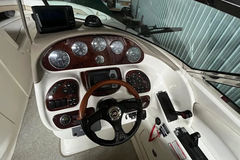 Slide: The Image of 2003 Sea Ray 290 Bowrider dashboard with wood accents and steering wheel. - 16