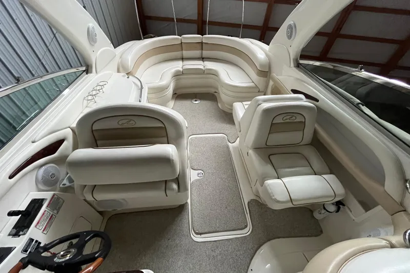 Slide: The Image of 2003 Sea Ray 290 Bowrider interior with beige seating and steering wheel in a covered area. - 19