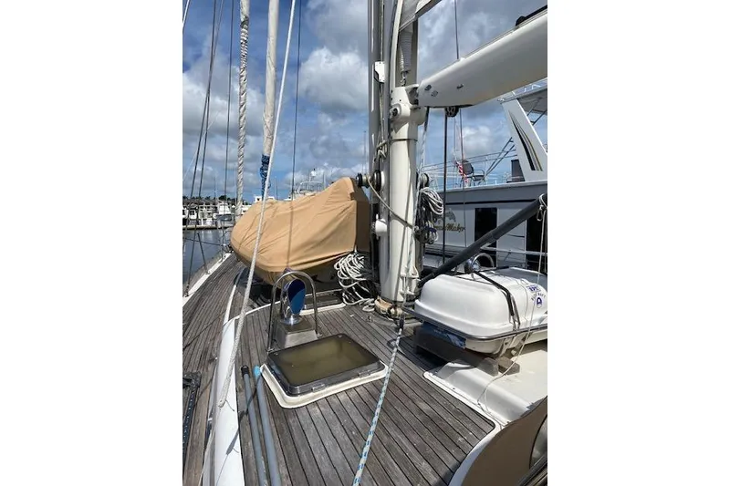 Slide: The Image of 1990 Little Harbor Sloop 58' sailboat deck with rigging and equipment, docked under cloudy skies. - 54