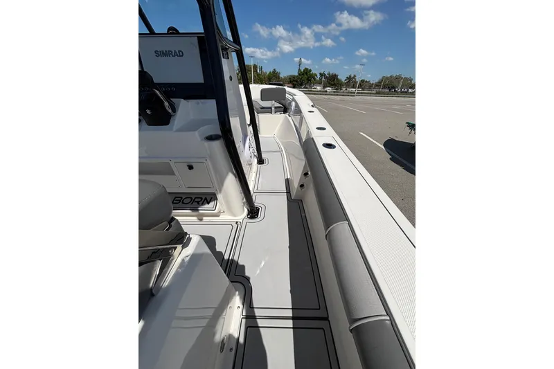 Slide: The Image of 2023 Sea Born LX24 Center Console boat interior with Simrad electronics, docked under blue sky. - 16