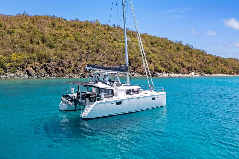 Slide: The Image of 2017 Lagoon 450 F catamaran sailing in clear turquoise waters near a lush coastline. - 5