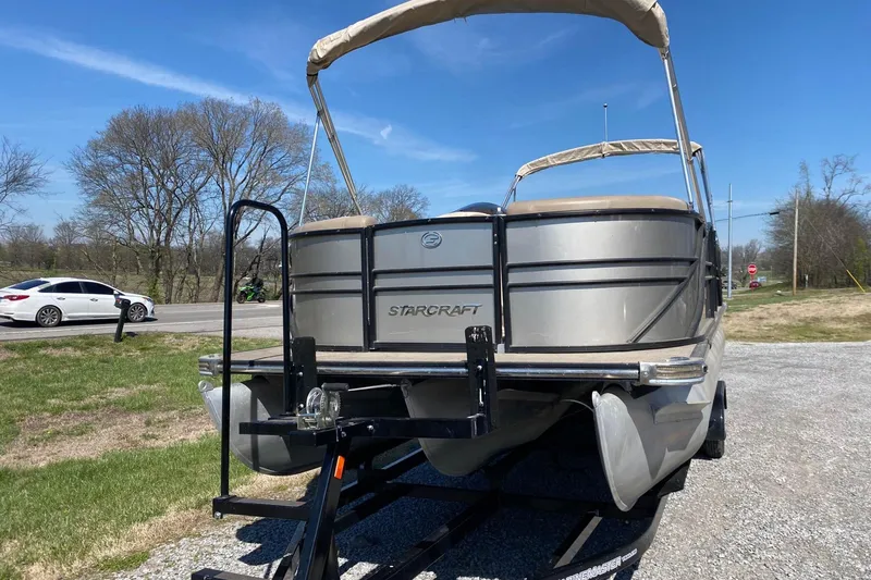 Slide: The Image of 2016 Starcraft MX 23 L pontoon boat on trailer, parked outdoors. - 2