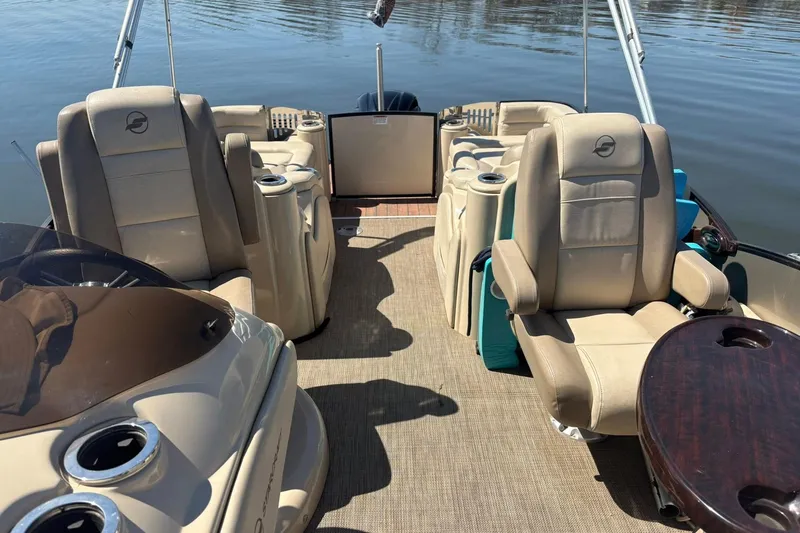 Slide: The Image of 2016 Starcraft MX 23 L boat interior with beige seating and wooden table on calm water. - 4