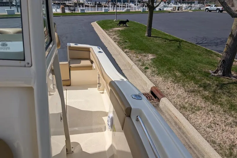 Slide: The Image of 2017 Scout 225 XSF boat docked near a marina with a grassy area. - 16
