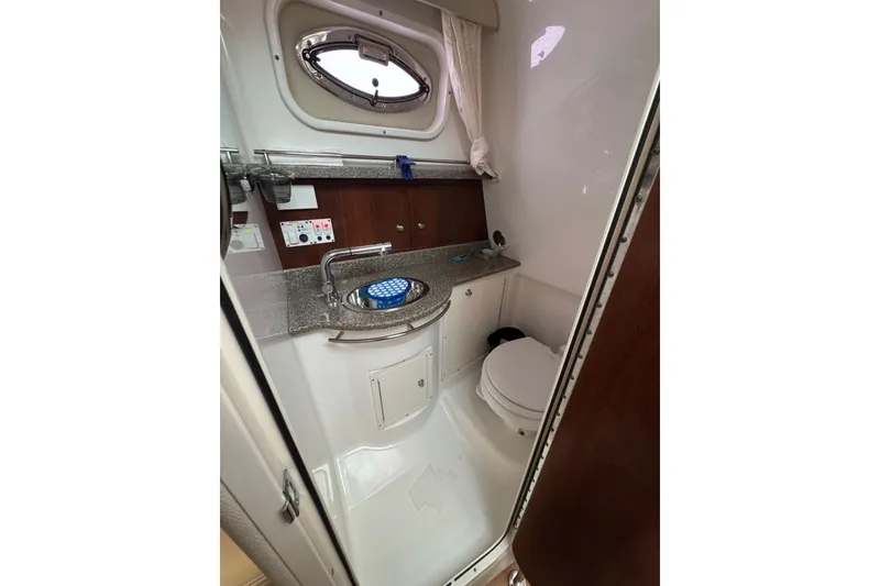 Slide: The Image of 2018 Robalo R305 Walkaround boat bathroom with sink, toilet, and porthole window. - 16