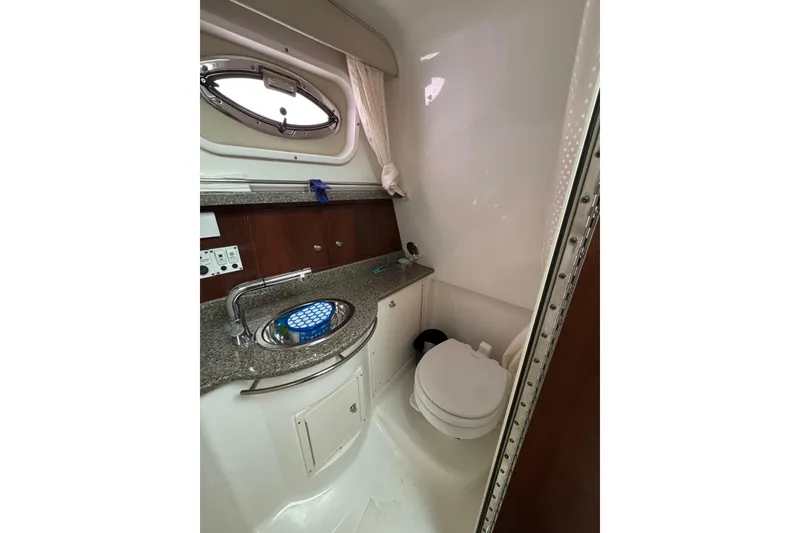 Slide: The Image of 2018 Robalo R305 Walkaround boat bathroom with sink, toilet, and porthole window. - 19