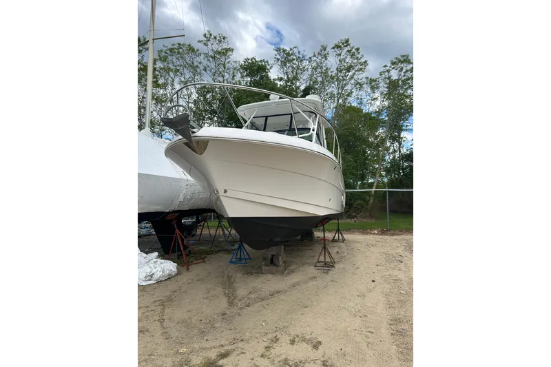 Slide: The Image of 2018 Robalo R305 Walkaround boat on stands, outdoors, with trees in the background. - 2