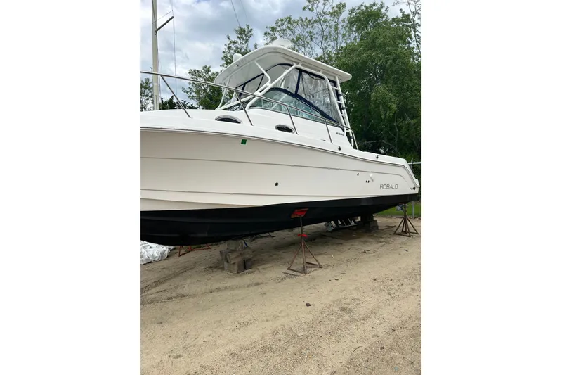 Slide: The Image of 2018 Robalo R305 Walkaround boat on stands, outdoors, with trees in background. - 3