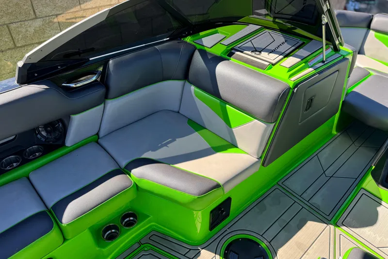 Slide: The Image of 2021 Moomba Kaiyen boat interior with vibrant green and gray seating, cup holders, and dashboard. - 26