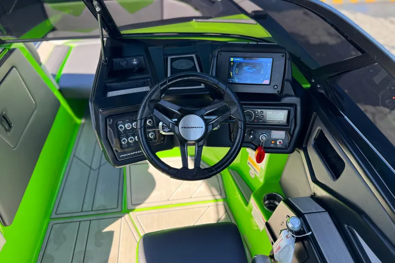 Slide: The Image of 2021 Moomba Kaiyen boat cockpit with steering wheel, controls, and navigation display. - 32