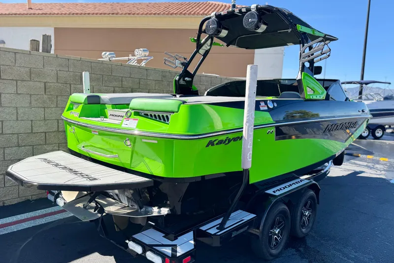 Slide: The Image of 2021 Moomba Kaiyen boat in vibrant green, parked on a trailer. - 5