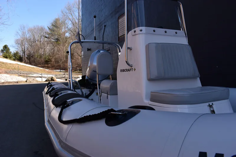 Slide: The Image of 2020 Ribcraft 5.85 inflatable boat with seating, parked outdoors near trees. - 7