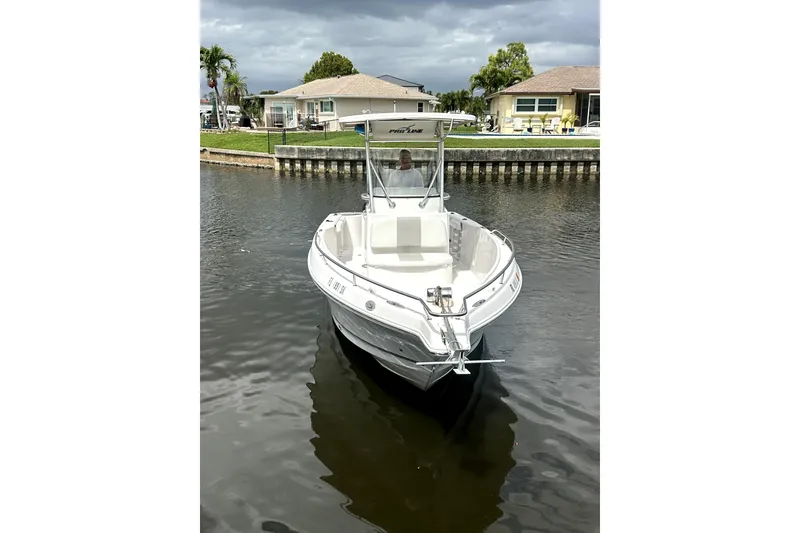 Slide: The Image of 2014 Pro-Line 26 Super Sport boat on a calm canal near residential homes. - 10