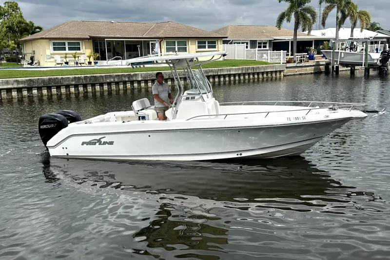 Slide: The Image of 2014 Pro-Line 26 Super Sport boat on a calm waterway, with houses and palm trees in the background. - 14