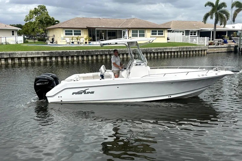 Slide: The Image of 2014 Pro-Line 26 Super Sport boat cruising on a canal near waterfront homes. - 15