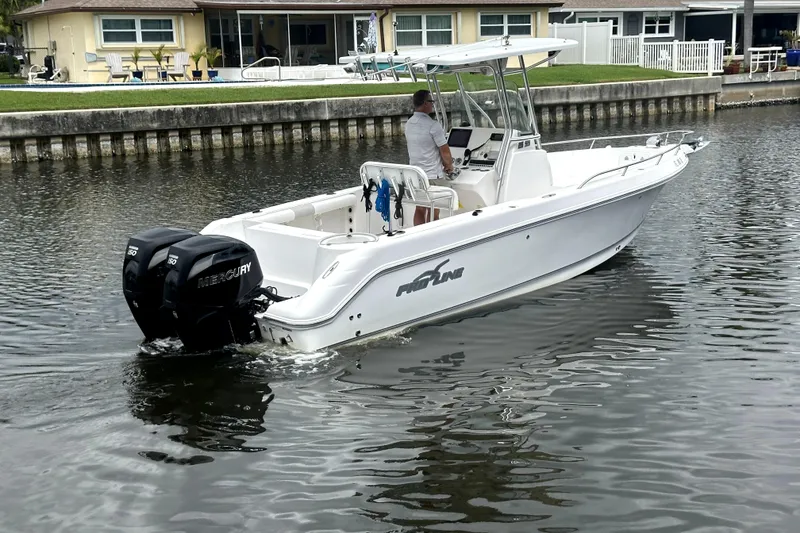 Slide: The Image of 2014 Pro-Line 26 Super Sport boat with dual Mercury engines on a calm waterway. - 17