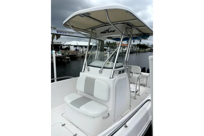 Slide: The Image of 2014 Pro-Line 26 Super Sport boat with T-top and seating, docked by the water. - 28