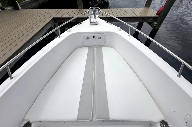 Slide: The Image of 2014 Pro-Line 26 Super Sport boat bow with white seating, docked by wooden pier. - 30