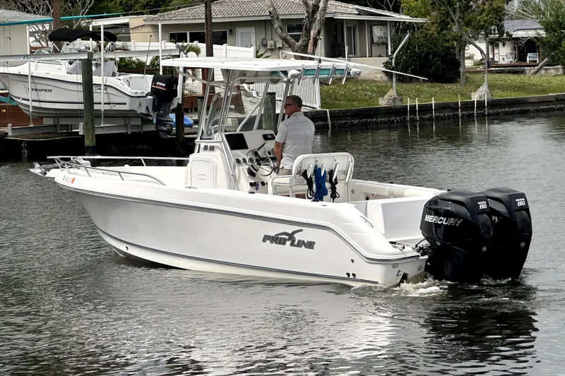 Slide: The Image of 2014 Pro-Line 26 Super Sport boat with dual Mercury engines on a calm waterway. - 4