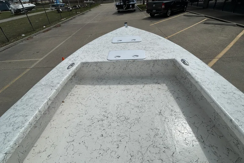Slide: The Image of 2026 Coastal Skiff 231 Flats boat deck with textured surface in a parking area. - 14