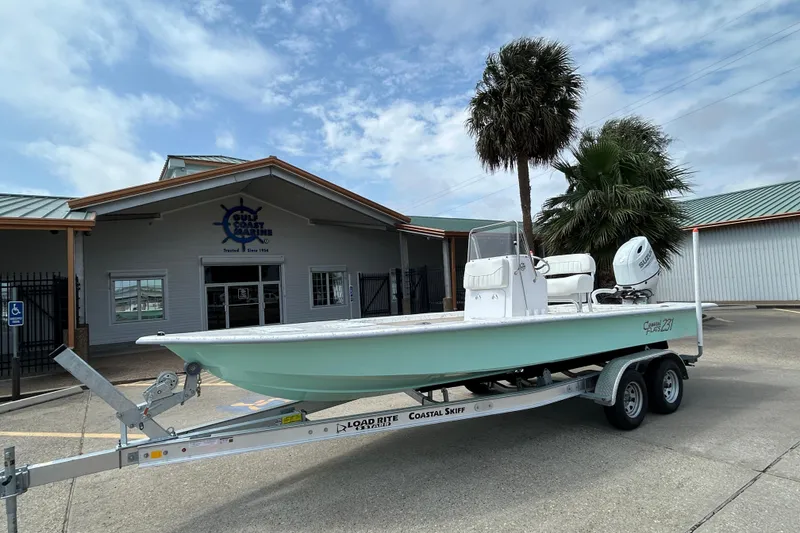 Slide: The Image of 2026 Coastal Skiff 231 Flats boat on trailer outside maritime building. - 3