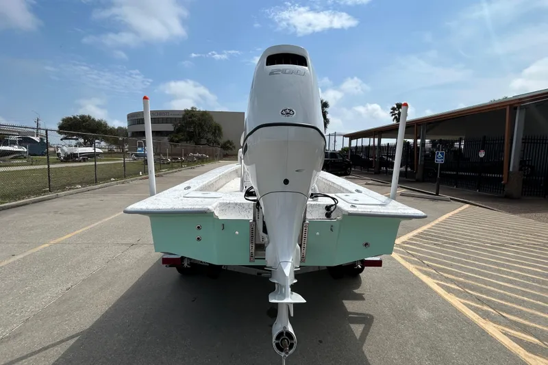 Slide: The Image of 2026 Coastal Skiff 231 Flats boat with powerful outboard motor, parked on a sunny day. - 5