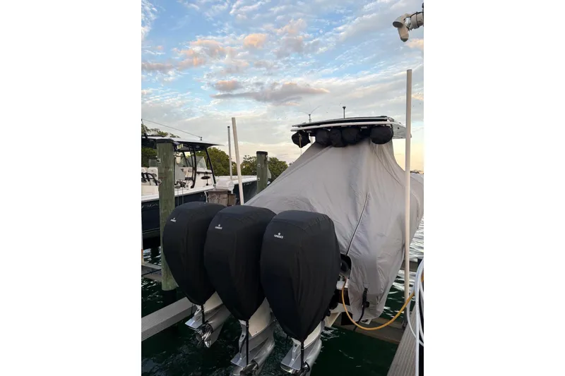 Slide: The Image of Covered 2021 Renegade 33 boat docked with triple outboard motors. - 10