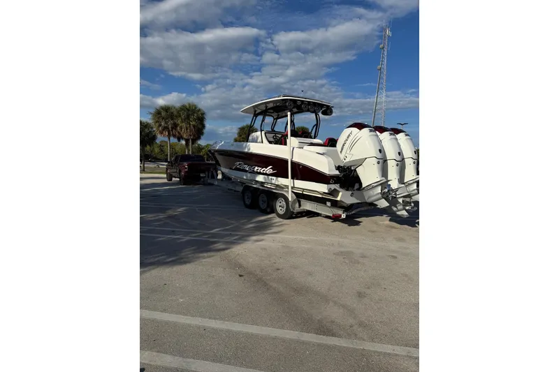 Slide: The Image of 2021 Renegade 33 boat on trailer with triple Mercury engines, parked under blue sky. - 12