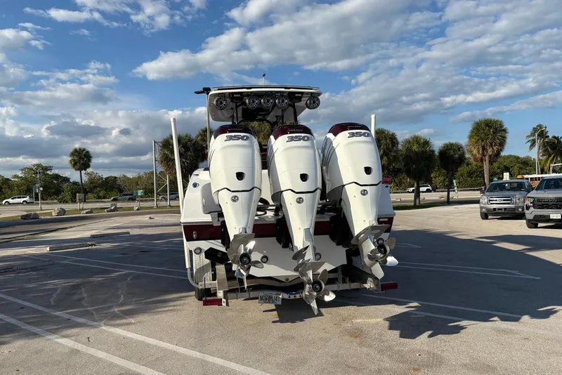 Slide: The Image of 2021 Renegade 33 boat with triple 350 horsepower engines in a sunny parking lot. - 19