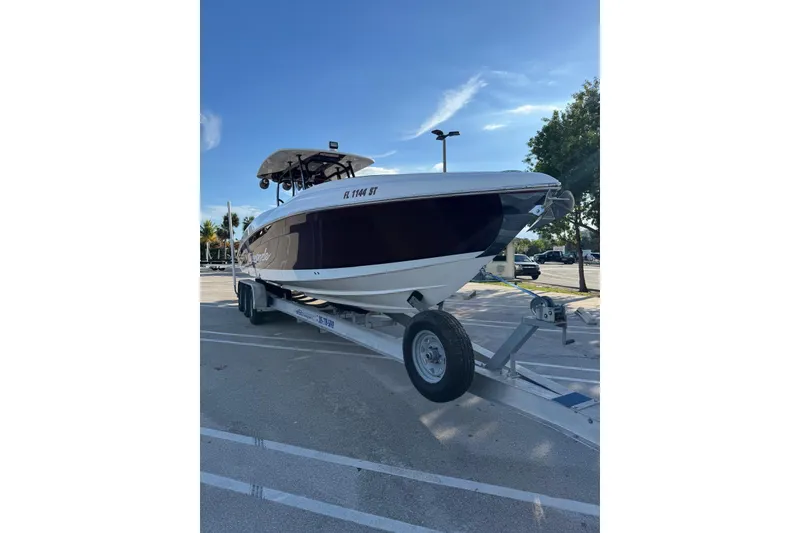Slide: The Image of 2021 Renegade 33 boat on trailer in parking lot under clear sky. - 3