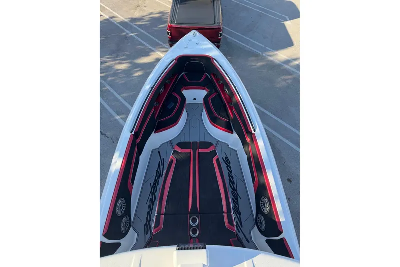Slide: The Image of 2021 Renegade 33 boat interior with red and black seating, parked on pavement. - 6