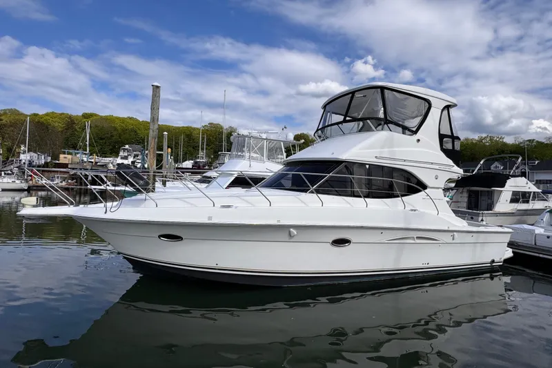 The Image of 2004 Silverton 38 Convertible yacht docked in a marina under a partly cloudy sky. - 0