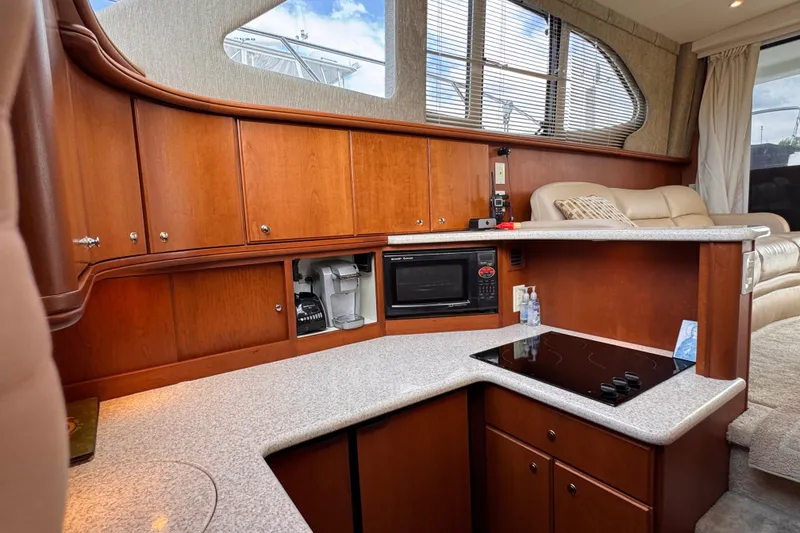 Slide: The Image of 2004 Silverton 38 Convertible yacht interior with kitchenette, featuring wood cabinetry and modern appliances. - 17