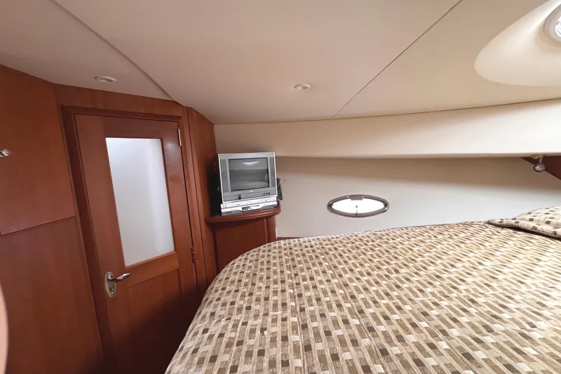 Slide: The Image of Interior of 2004 Silverton 38 Convertible yacht with TV and patterned bedding. - 26